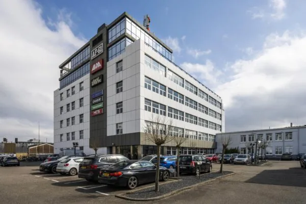 Kantoorgebouw aan de Anthony Fokkerweg met meerdere bedrijfslogo’s en een parkeerplaats op de voorgrond.